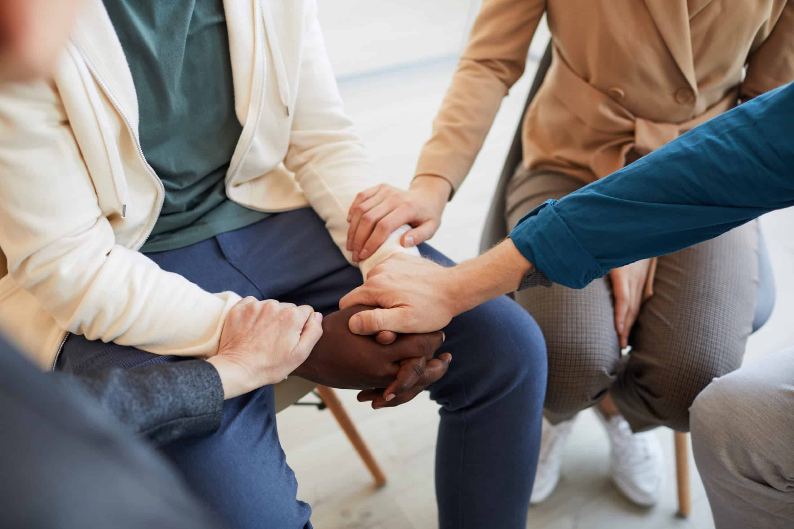 High angle closeup of people holding hands while comforting each other in psychology support group, copy space